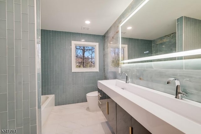 full bath with toilet, marble finish floor, a washtub, tile walls, and recessed lighting