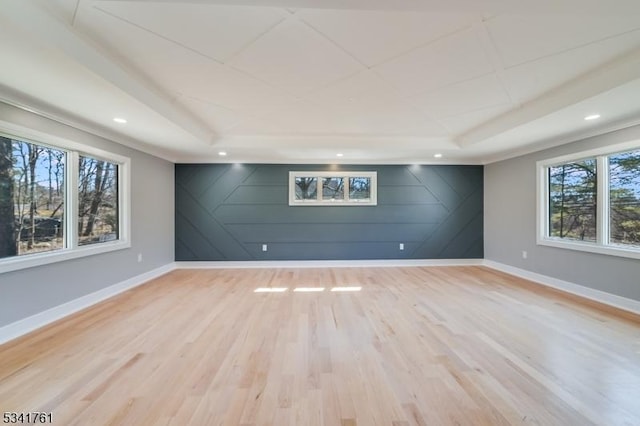 unfurnished room featuring a tray ceiling, light wood-style flooring, and baseboards