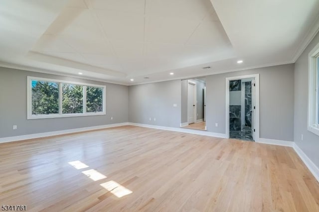 unfurnished room with light wood finished floors, baseboards, a raised ceiling, crown molding, and recessed lighting