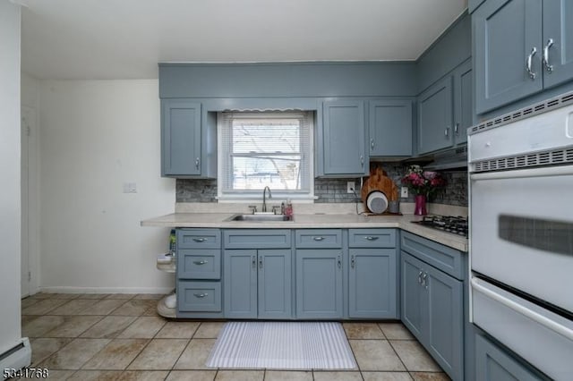 kitchen featuring light countertops, baseboard heating, a sink, and backsplash