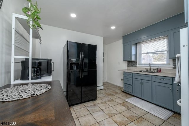 kitchen featuring light tile patterned floors, black fridge with ice dispenser, a sink, backsplash, and recessed lighting