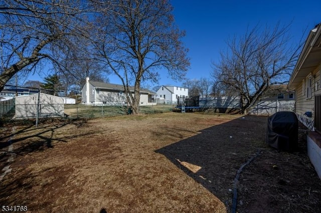 view of yard featuring a trampoline and fence