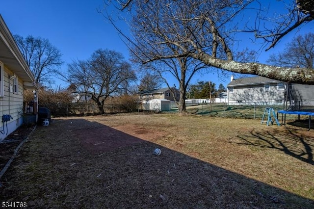 view of yard featuring a storage shed, a trampoline, an outdoor structure, and a fenced backyard