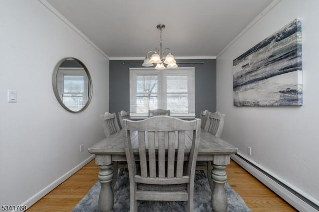 dining room featuring an inviting chandelier, a baseboard heating unit, ornamental molding, wood finished floors, and baseboards