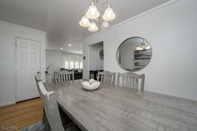 dining space featuring crown molding, a chandelier, and wood finished floors