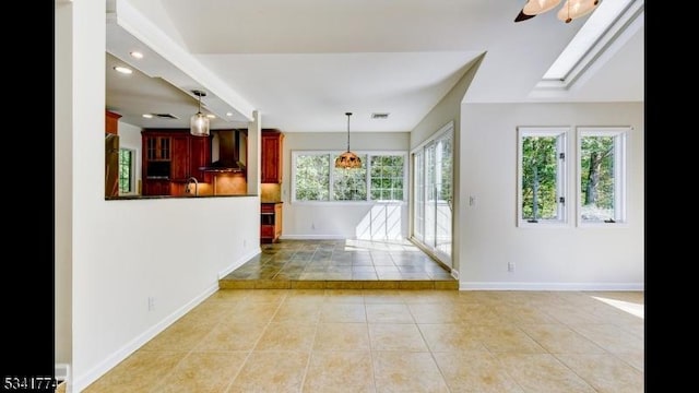 interior space with visible vents, baseboards, light tile patterned floors, a skylight, and a ceiling fan