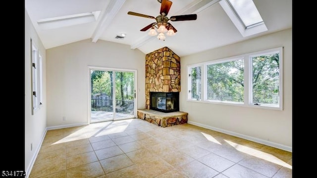 unfurnished living room with tile patterned floors, vaulted ceiling with skylight, a fireplace, baseboards, and ceiling fan