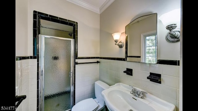 full bath featuring toilet, ornamental molding, a sink, tile walls, and a shower stall