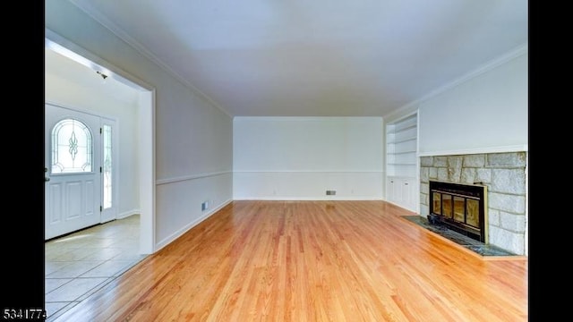 unfurnished living room featuring built in features, a fireplace, wood finished floors, and ornamental molding