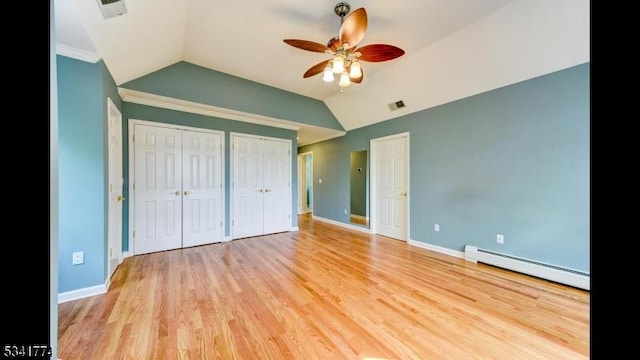 unfurnished bedroom featuring lofted ceiling, light wood-style flooring, two closets, and a baseboard radiator