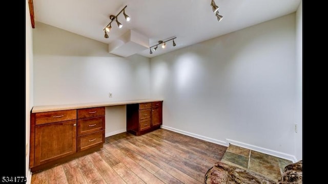 home office featuring built in study area, baseboards, and wood finished floors