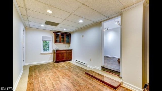 spare room featuring a paneled ceiling, light wood-type flooring, baseboards, and baseboard heating