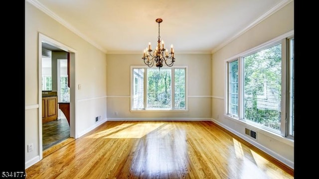 unfurnished dining area featuring light wood finished floors, visible vents, baseboards, ornamental molding, and a notable chandelier