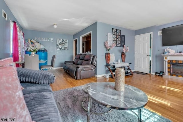 living room featuring visible vents, baseboards, wood finished floors, and a fireplace