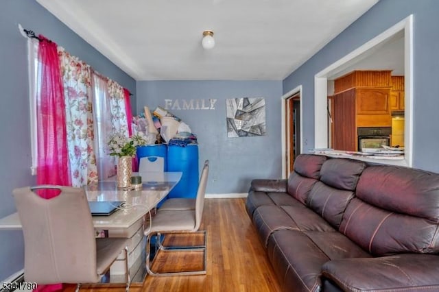 dining area featuring a baseboard heating unit, baseboards, and wood finished floors