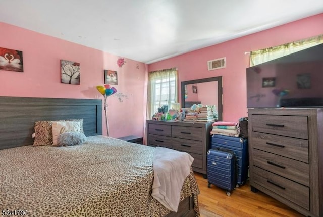 bedroom with light wood-style floors and visible vents