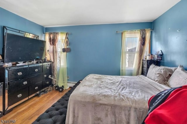 bedroom with a baseboard radiator and wood finished floors