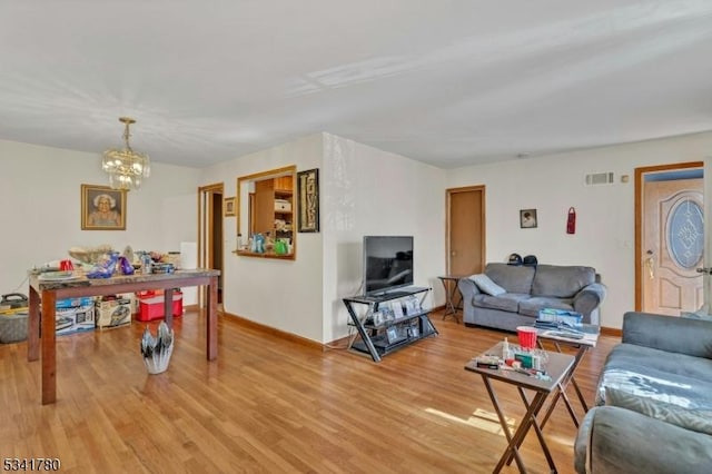 living room featuring an inviting chandelier, light wood-style floors, visible vents, and baseboards