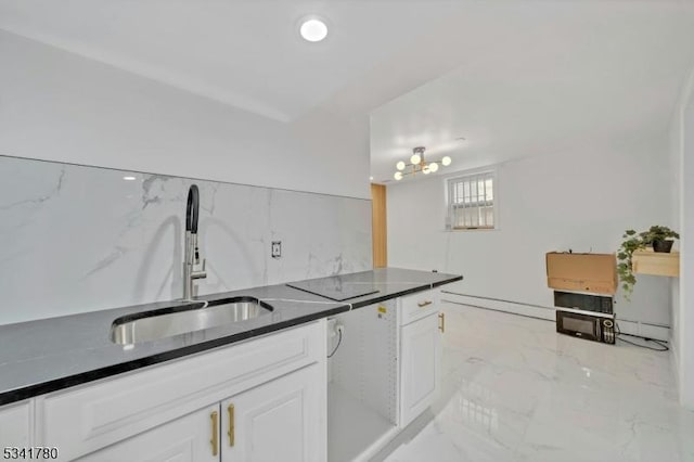 kitchen with a sink, dark countertops, marble finish floor, and white cabinets