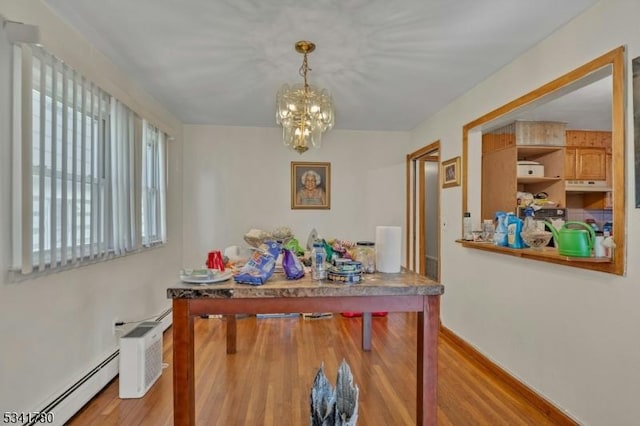 dining space with a chandelier, a baseboard heating unit, and wood finished floors