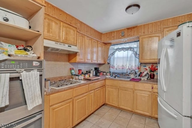 kitchen with under cabinet range hood, stainless steel appliances, light tile patterned flooring, and light countertops