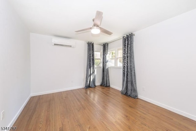 spare room with ceiling fan, baseboards, wood finished floors, and a wall mounted AC