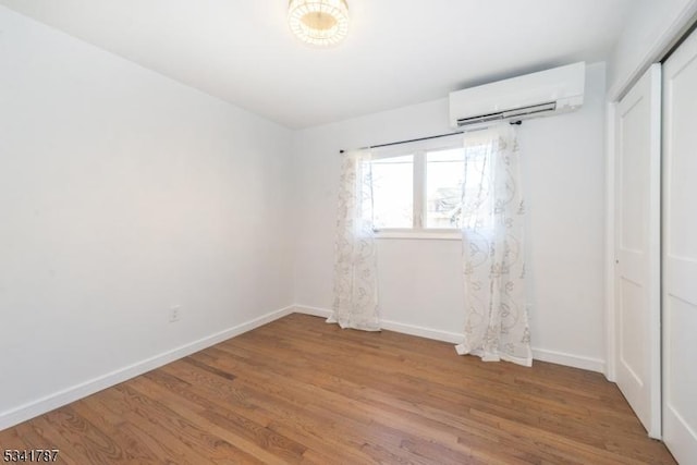 spare room with light wood-style floors, baseboards, and an AC wall unit