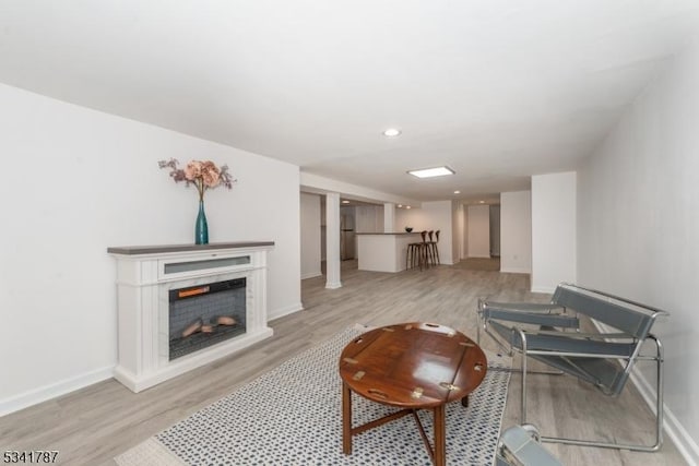 living room featuring baseboards, recessed lighting, a fireplace, and light wood-style floors