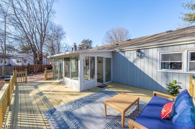 wooden terrace featuring outdoor lounge area, fence, and a sunroom