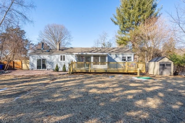 rear view of property with a storage shed, a chimney, fence, a deck, and an outdoor structure