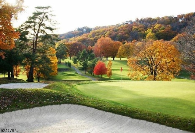 view of community featuring view of golf course and a yard