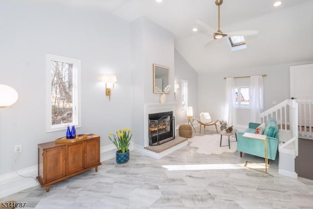 sitting room featuring high vaulted ceiling, a glass covered fireplace, marble finish floor, and recessed lighting