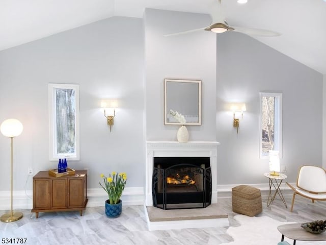 living area with lofted ceiling, ceiling fan, and a warm lit fireplace