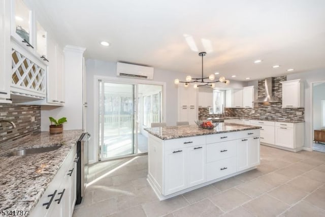 kitchen with white cabinets, a wall mounted air conditioner, a sink, and wall chimney exhaust hood