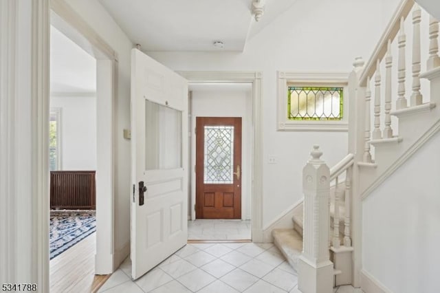 foyer with light tile patterned floors, stairs, and baseboards