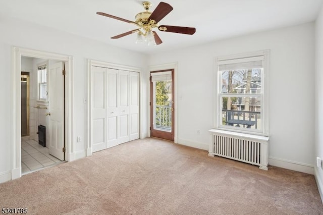 unfurnished bedroom featuring connected bathroom, carpet floors, a ceiling fan, access to exterior, and radiator heating unit