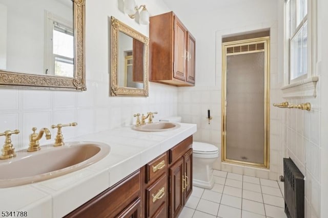 bathroom featuring tile walls, radiator, toilet, a sink, and a shower stall