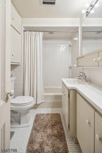 bathroom with toilet, tile walls, vanity, tile patterned floors, and shower / tub combo with curtain