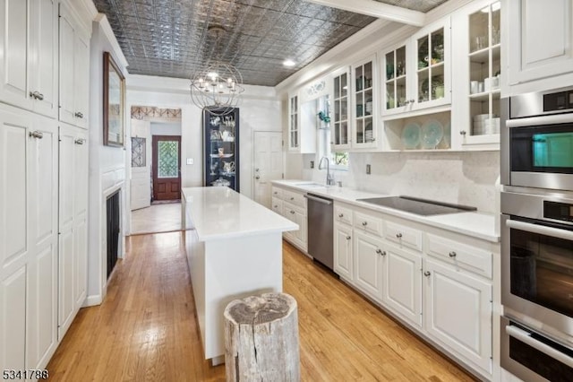 kitchen with stainless steel appliances, a kitchen island, white cabinets, a warming drawer, and an ornate ceiling