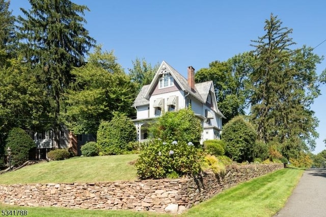 view of side of home featuring a lawn and a chimney