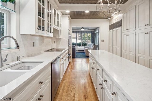 kitchen featuring tasteful backsplash, stainless steel dishwasher, white cabinetry, a sink, and light wood-type flooring