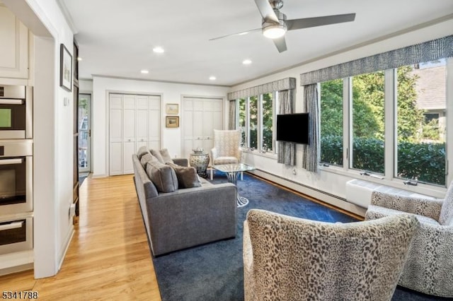 living area with light wood-type flooring, a baseboard radiator, a ceiling fan, and recessed lighting