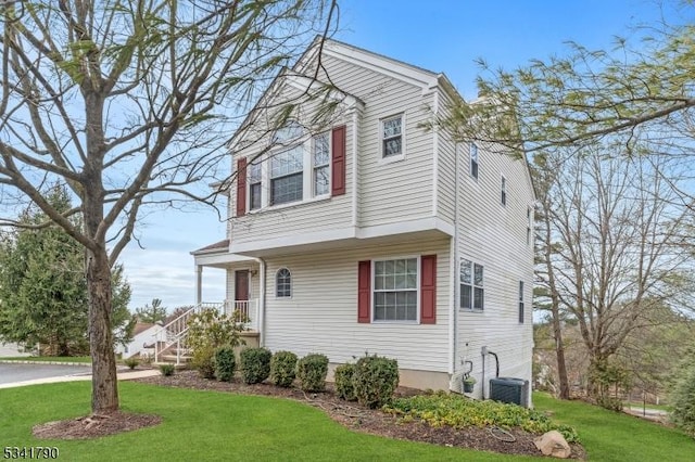 view of front of house with central AC unit and a front lawn