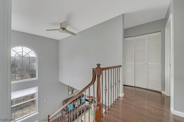 corridor featuring baseboards, an upstairs landing, and wood finished floors