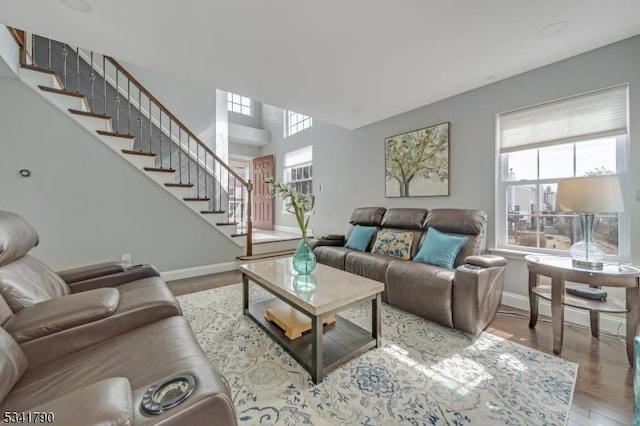 living area with a wealth of natural light, stairs, baseboards, and wood finished floors