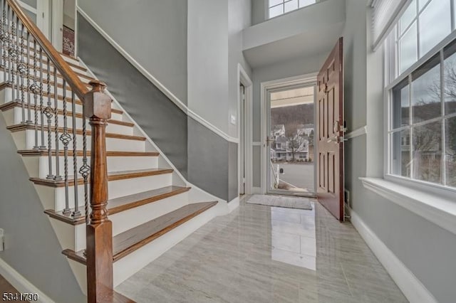 entrance foyer featuring plenty of natural light, stairway, a high ceiling, and baseboards