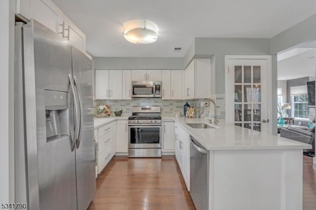 kitchen with dark wood-style flooring, a sink, light countertops, appliances with stainless steel finishes, and tasteful backsplash