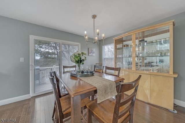 dining space with baseboards, wood finished floors, and a chandelier