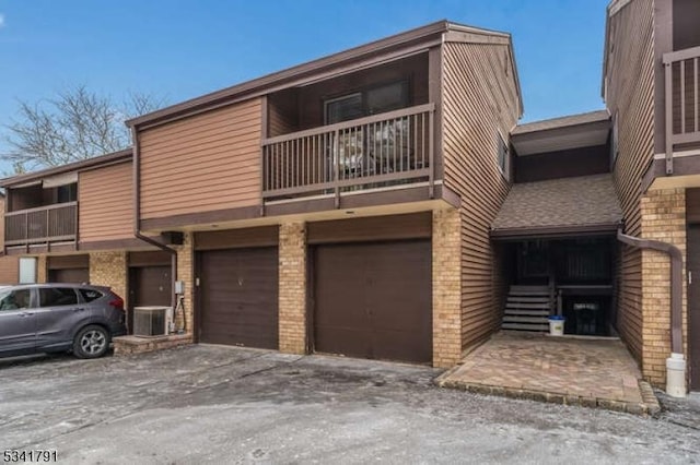 view of property with cooling unit, an attached garage, and driveway