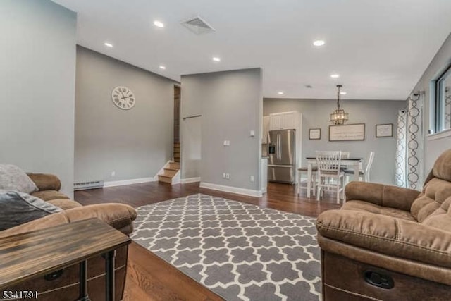 living room featuring visible vents, dark wood-type flooring, stairway, baseboard heating, and recessed lighting